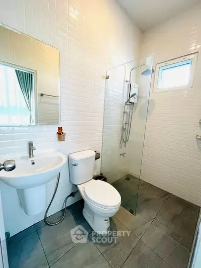 Modern bathroom with glass shower and sleek fixtures in a bright, tiled space.