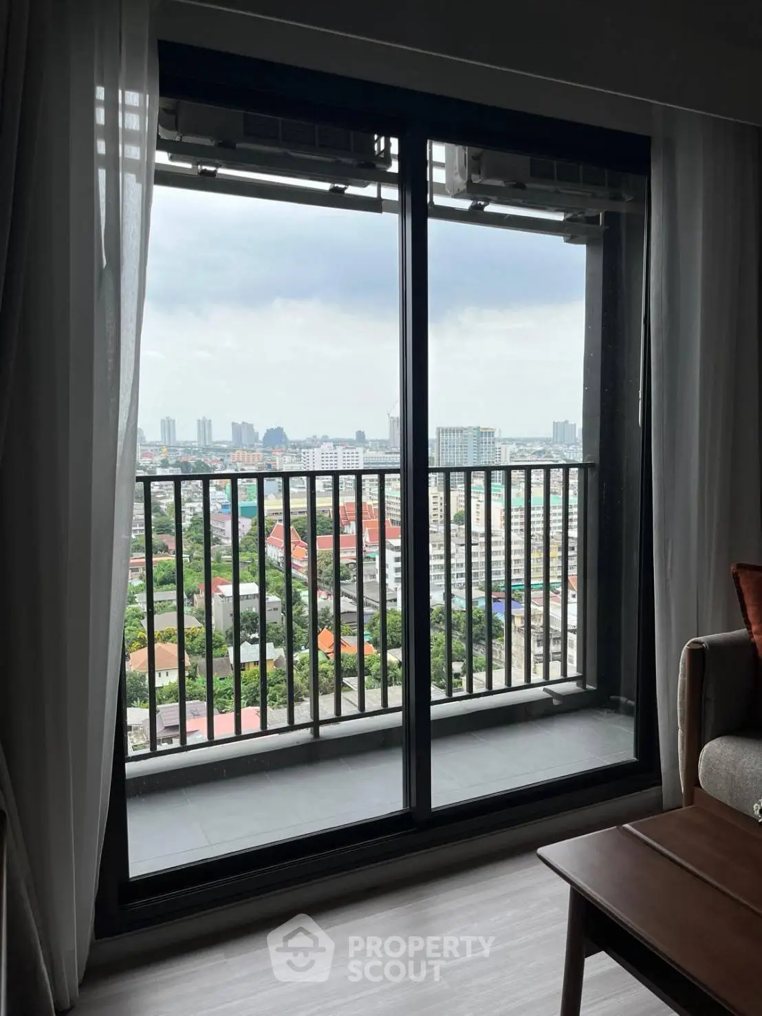 Stunning city view from modern apartment balcony with floor-to-ceiling windows.