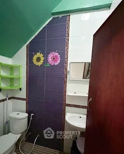 Charming bathroom with unique floral tile accents and compact design, perfect for cozy living spaces.