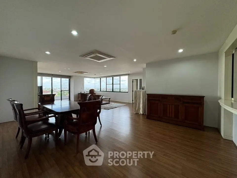 Spacious open-plan living room with elegant wooden furniture and panoramic city views.