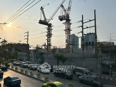 Urban construction site with cranes and city traffic at sunset