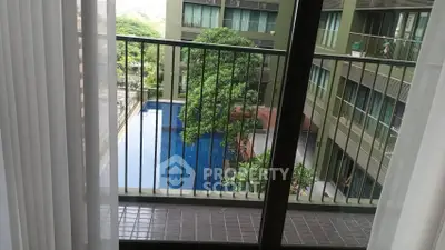 Modern apartment balcony with pool view and lush greenery