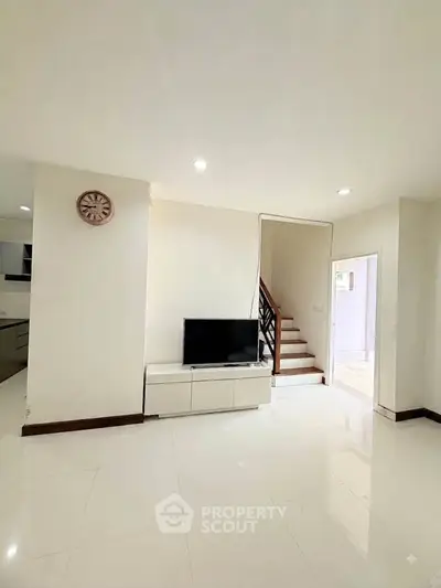 Spacious modern living room with sleek TV unit and staircase, perfect for family gatherings.