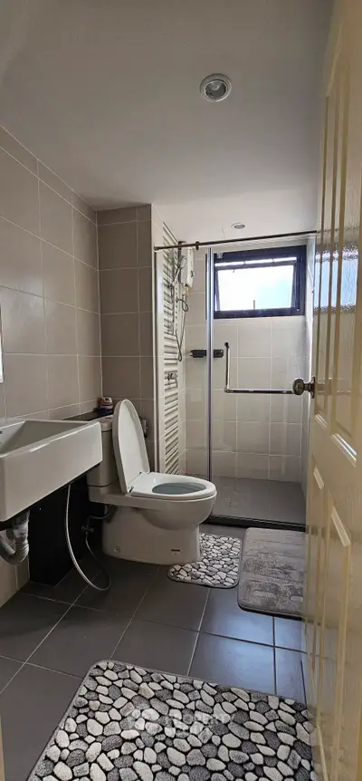 Modern bathroom with sleek fixtures and natural light, featuring a shower and stylish tiles.