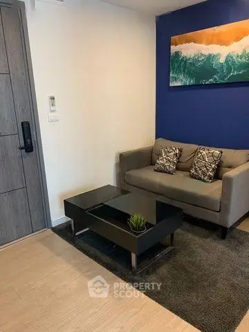 Modern living room with stylish sofa and coffee table, featuring a vibrant ocean wave painting.