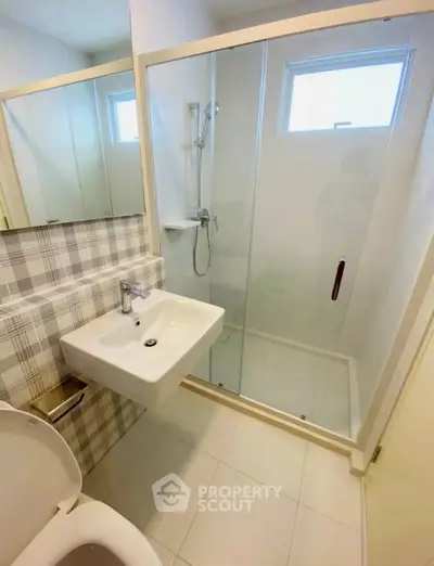 Modern bathroom with glass shower and stylish sink in a bright setting.
