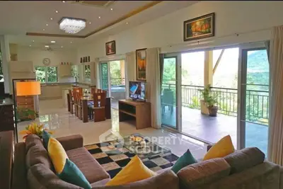 Spacious open-plan living room with balcony and scenic view, modern decor, and ample natural light.