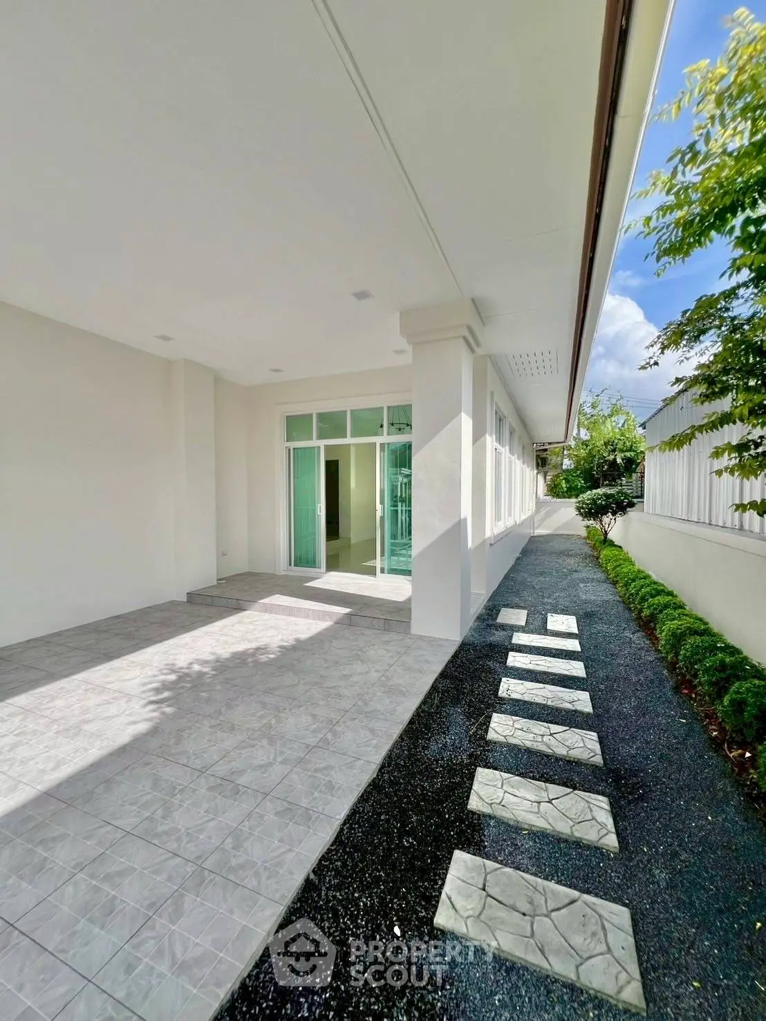 Spacious modern home entrance with sleek tiled pathway and lush greenery