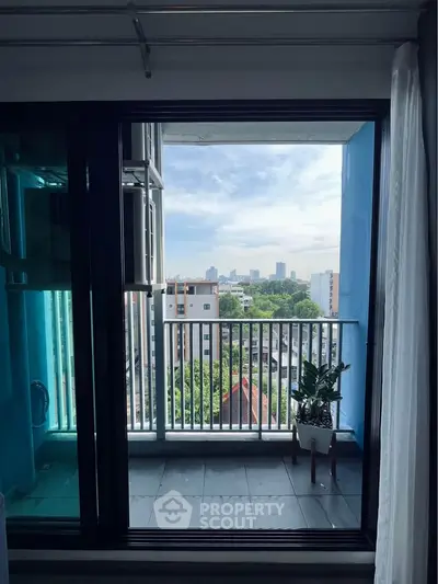 Modern apartment balcony with stunning city view and lush greenery.
