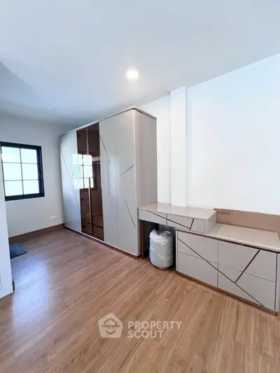 Modern bedroom with sleek built-in wardrobe and wooden flooring, perfect for stylish living.