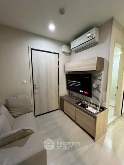Modern living room with sleek furniture and wall-mounted TV, featuring a cozy ambiance and efficient use of space.