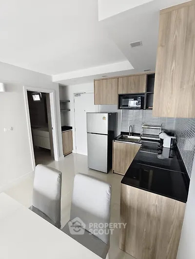 Modern kitchen with sleek wooden cabinets and stainless steel appliances in a stylish apartment.