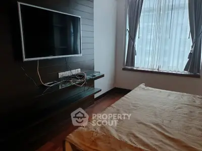 Modern bedroom with wall-mounted TV and large window with curtains
