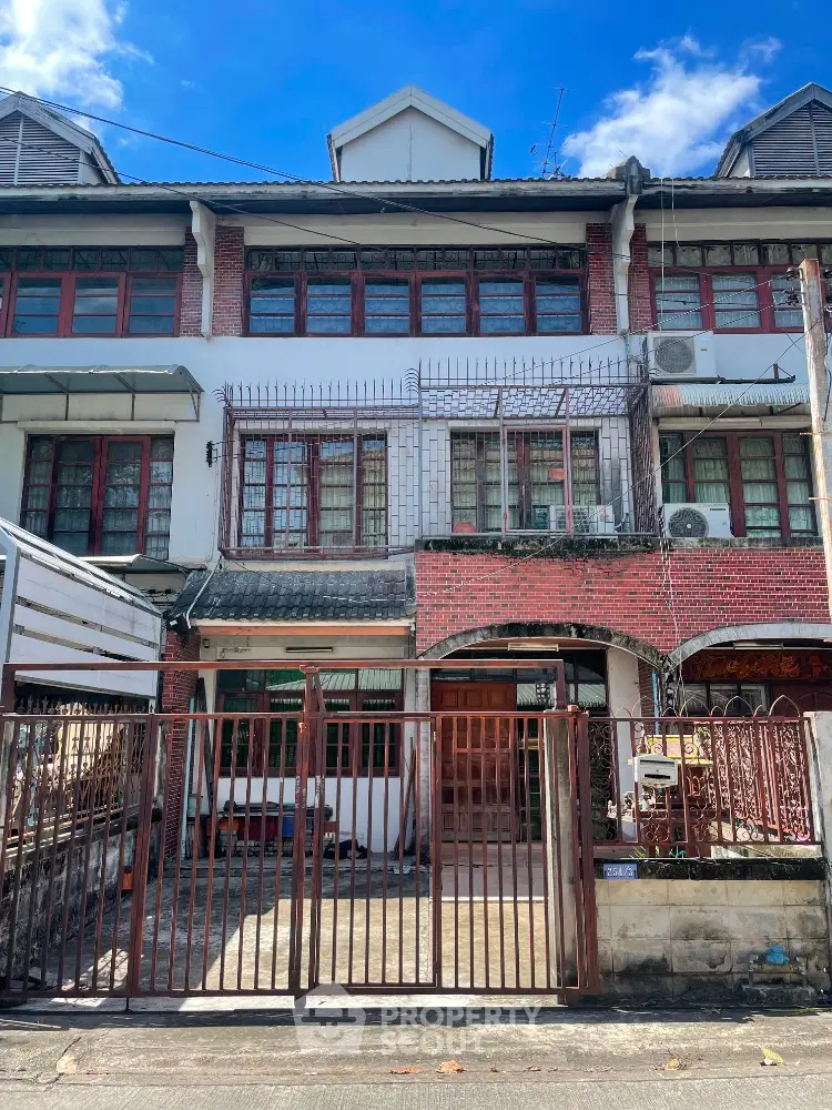 Charming three-story townhouse with gated entrance and classic brick facade in a serene neighborhood.