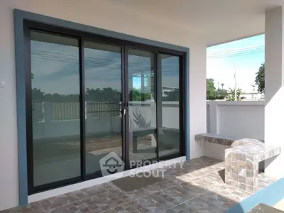 Modern patio with sliding glass doors and tiled flooring, perfect for outdoor relaxation.