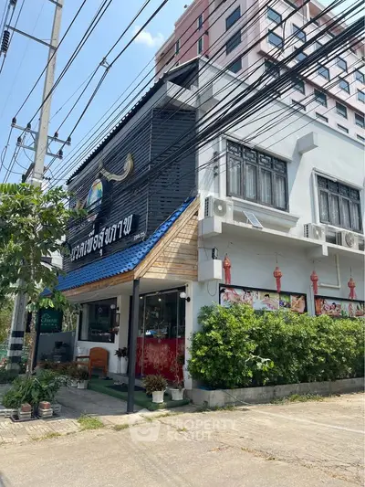 Charming commercial building with modern facade and lush greenery in urban setting.