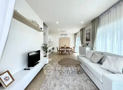 Spacious modern living room with elegant decor and dining area, featuring large windows and cozy seating.