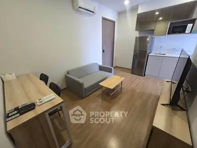 Modern living room with open kitchen, featuring sleek furniture and appliances in a cozy apartment setting.