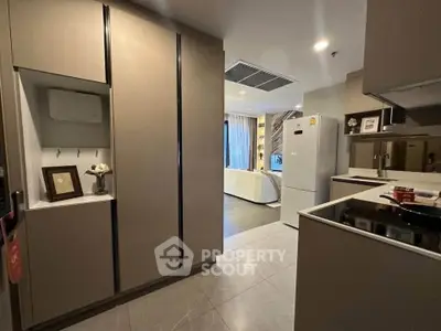 Modern kitchen with sleek cabinetry and open layout leading to a cozy living area.