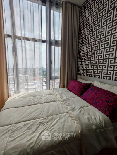 Stylish bedroom with large window and patterned wallpaper, offering a cozy and modern living space.