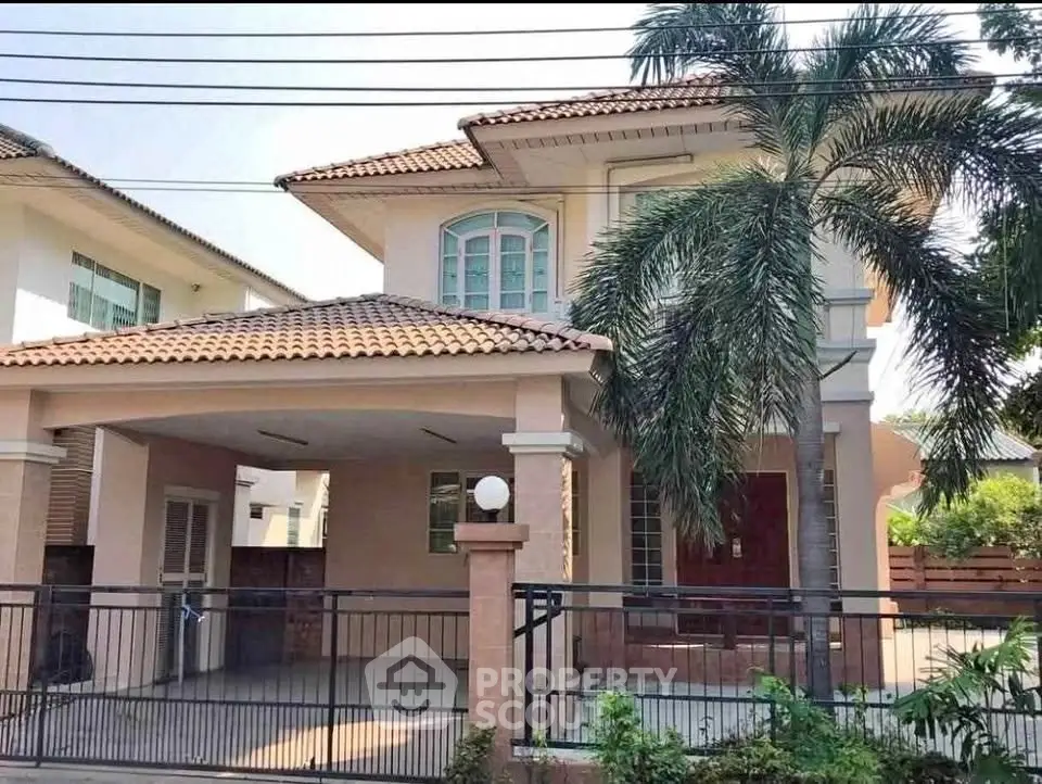 Charming two-story house with tiled roof and palm trees in front yard
