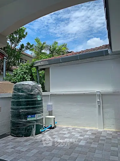 Spacious outdoor area with water tank and tiled flooring, perfect for utility or storage use.