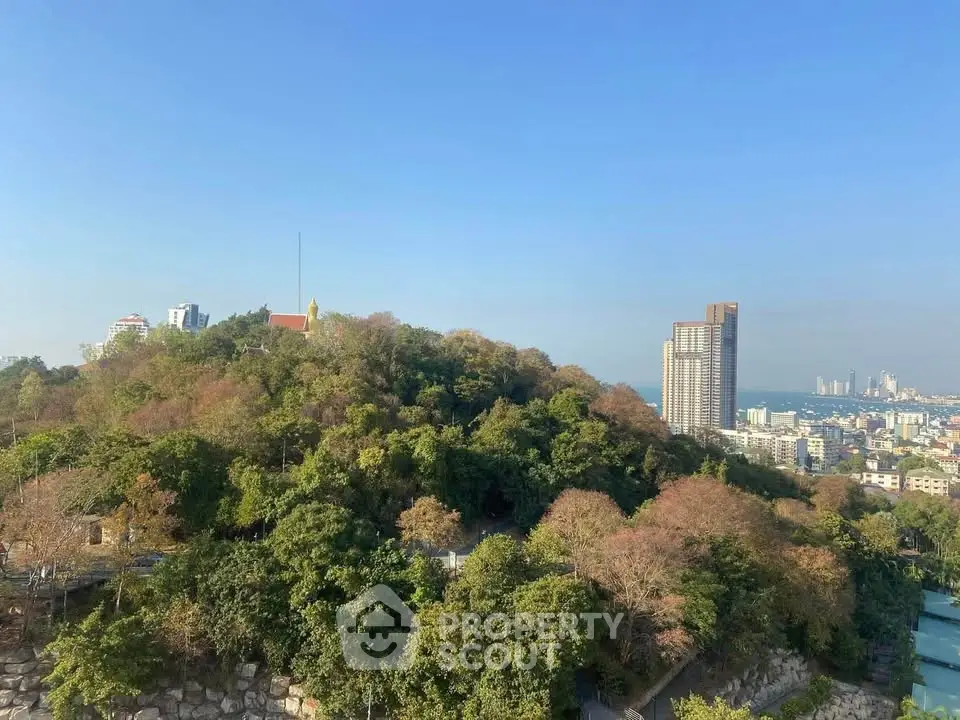 Stunning cityscape view with lush greenery and distant skyscrapers under clear blue sky.
