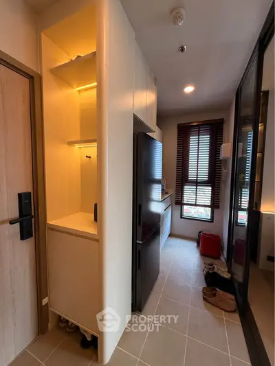 Modern apartment hallway with sleek storage and kitchen view