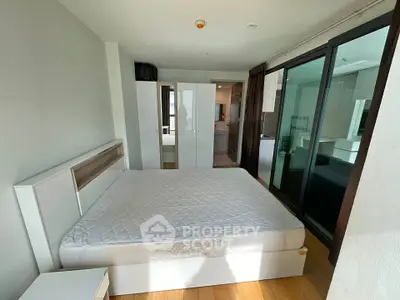 Spacious bedroom with modern furnishings and ample natural light, featuring a large bed and wardrobe.