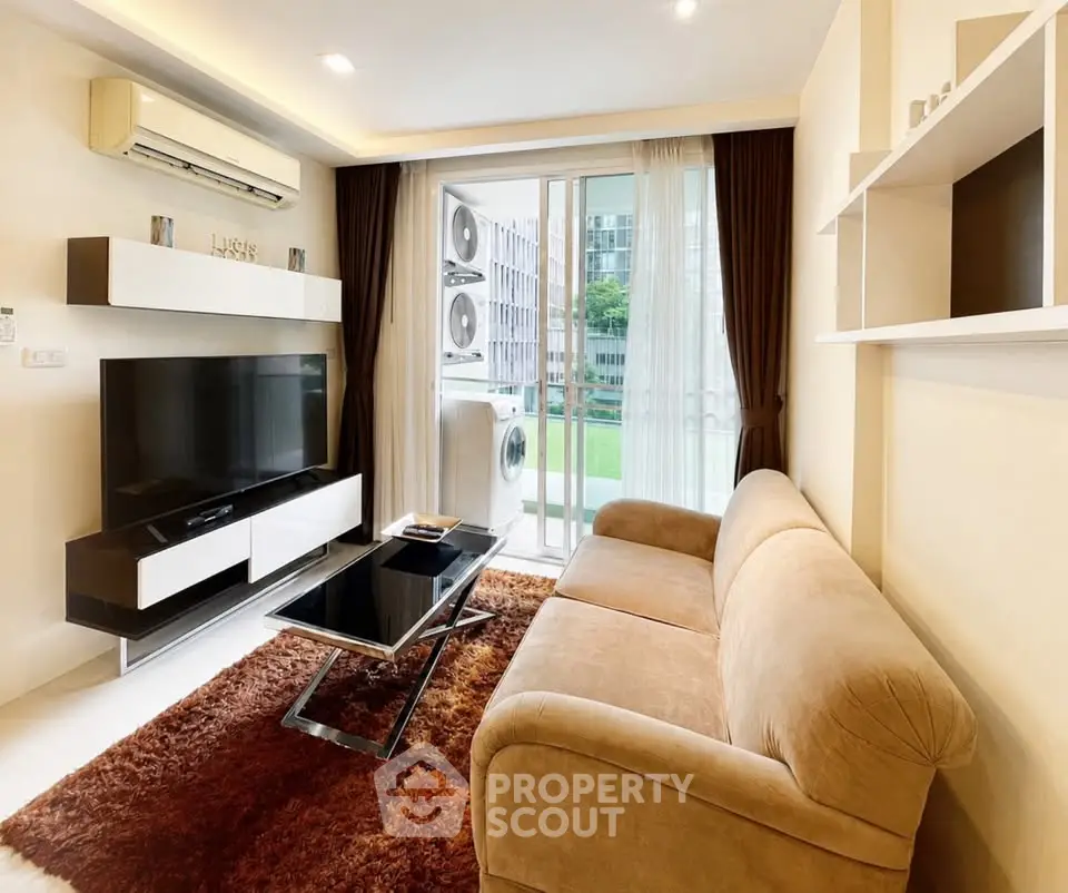 Modern living room with plush sofa, sleek TV unit, and large windows overlooking greenery.