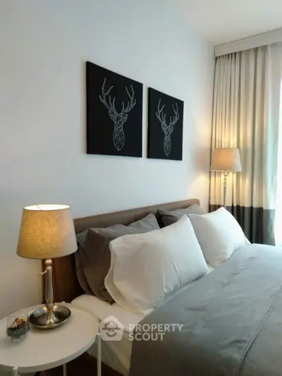 Modern bedroom with stylish decor and elegant lighting, featuring deer artwork above the bed.