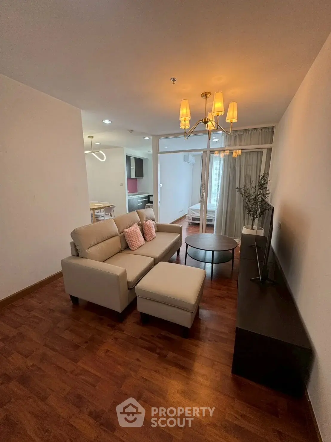Modern living room with elegant chandelier and cozy seating area in a stylish apartment.