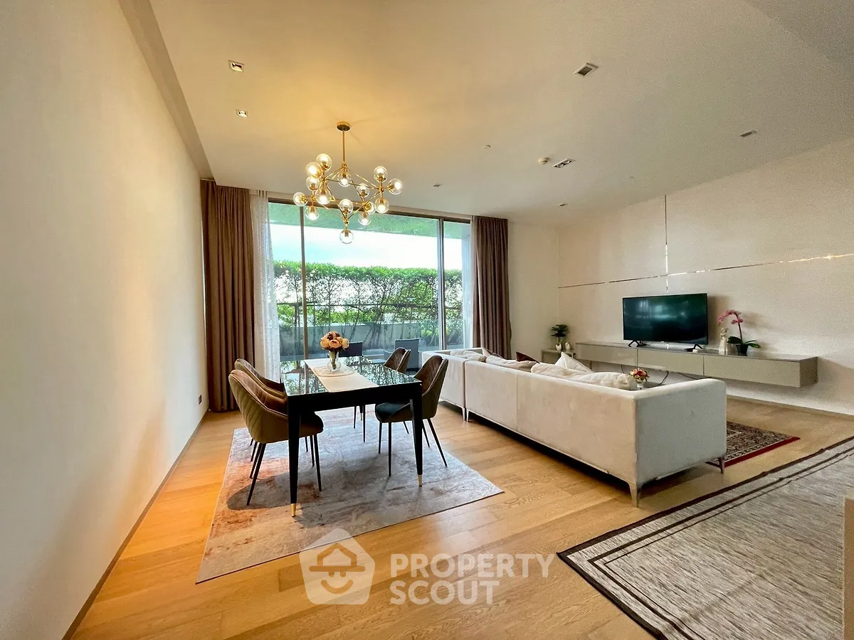 Spacious modern living room with elegant dining area and large windows overlooking greenery.