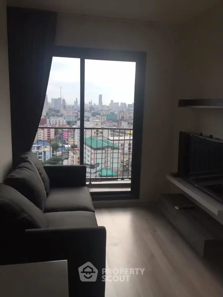 Modern living room with city view from balcony, featuring sleek furniture and large windows.