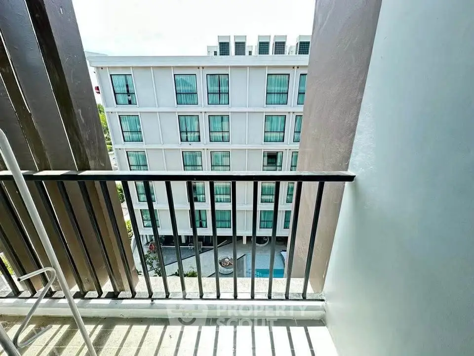 Modern apartment building view from balcony with sleek design and pool area.