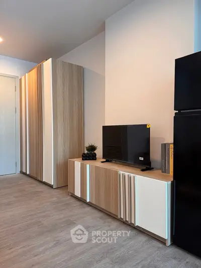 Modern living room with sleek furniture and stylish decor, featuring a flat-screen TV and wooden flooring.