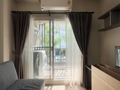 Cozy living room with balcony view and air conditioning, perfect for relaxation.