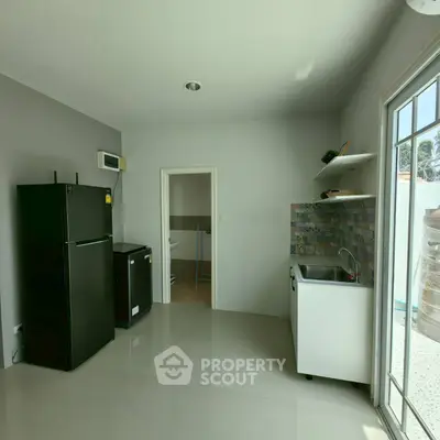 Modern kitchen with sleek black fridge and stylish backsplash in bright, airy space.