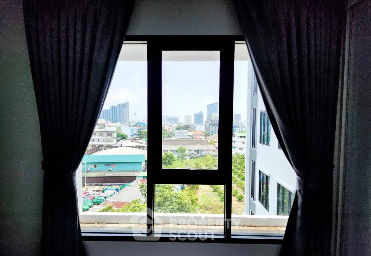 Stunning cityscape view from a modern apartment window with elegant curtains framing the skyline.