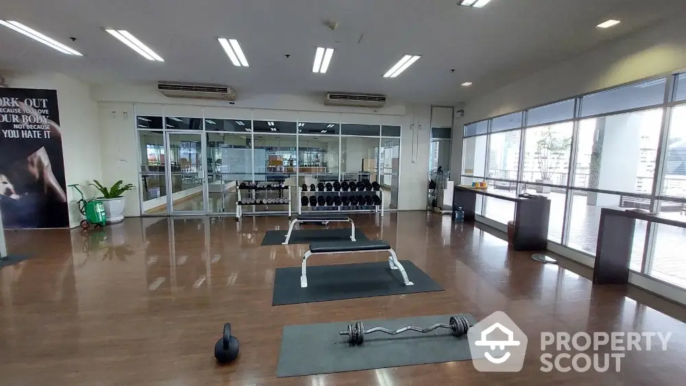 Spacious gym with modern equipment and large windows offering city views