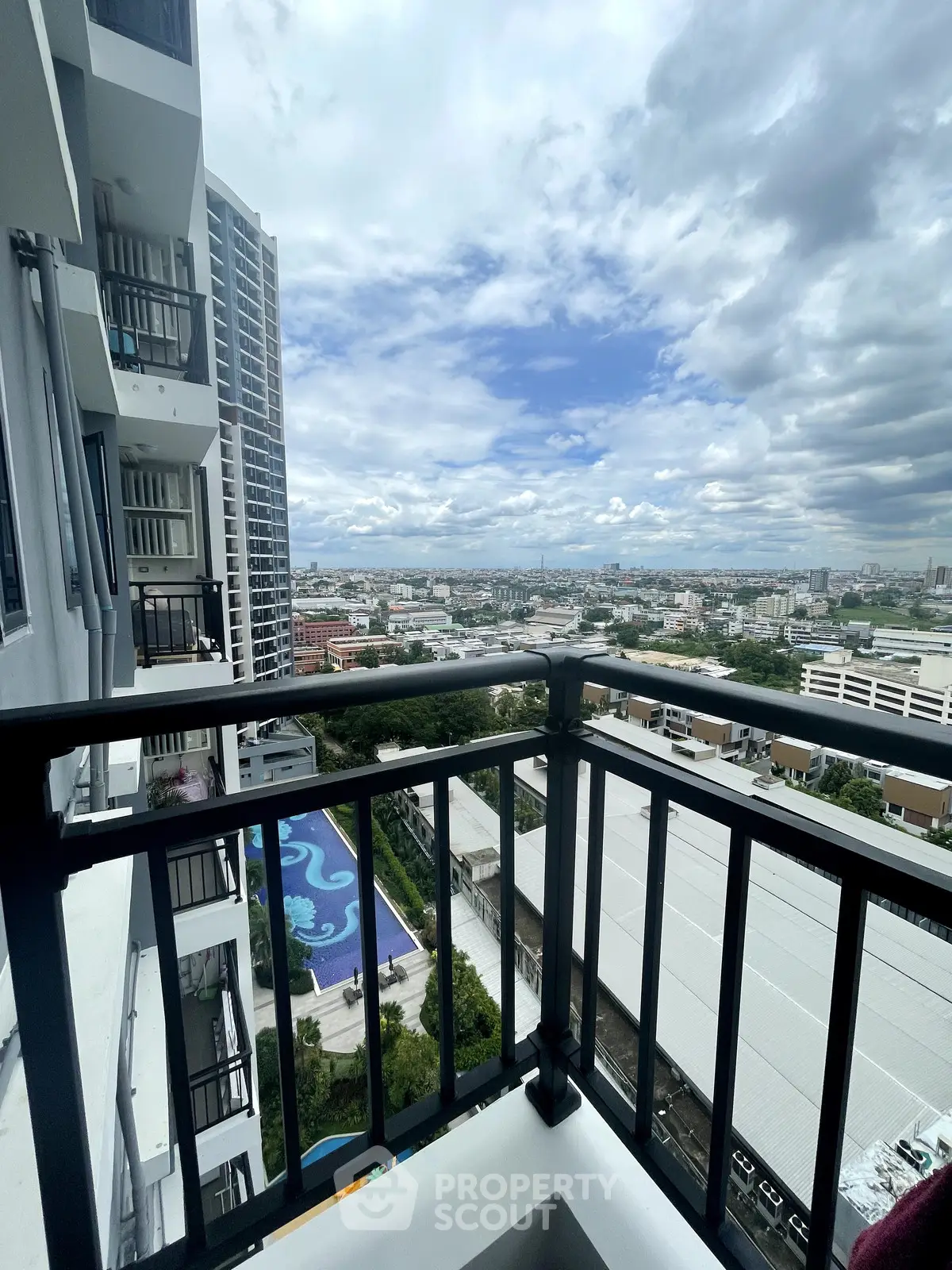 Stunning city view from high-rise balcony overlooking pool and skyline.