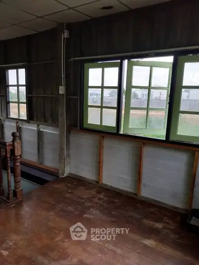 Charming rustic interior with wooden floors and large windows offering natural light and countryside views.