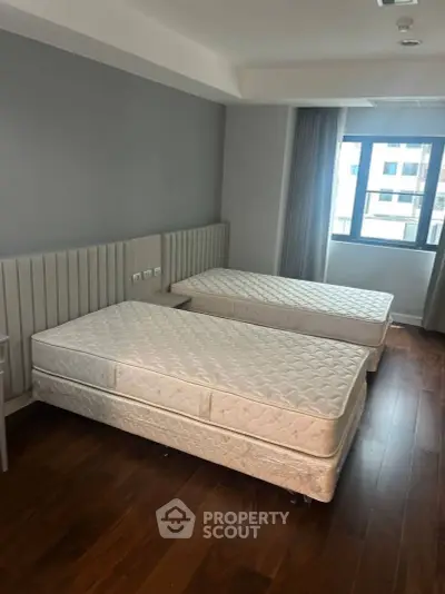 Spacious bedroom with twin beds and large window offering natural light.