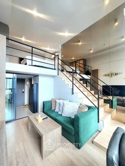 Modern loft apartment with stylish green sofa and wooden staircase leading to mezzanine bedroom.