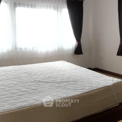 Bright bedroom with large window and simple decor, perfect for relaxation.