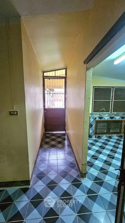 Charming hallway leading to a cozy kitchen with unique tile flooring in a welcoming home.