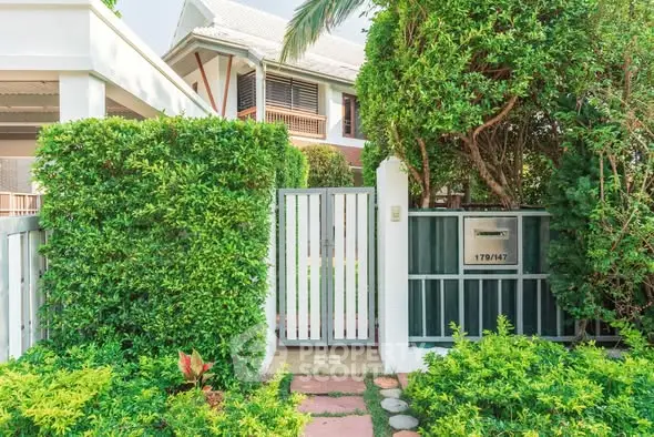 Charming house entrance with lush greenery and modern gate design.