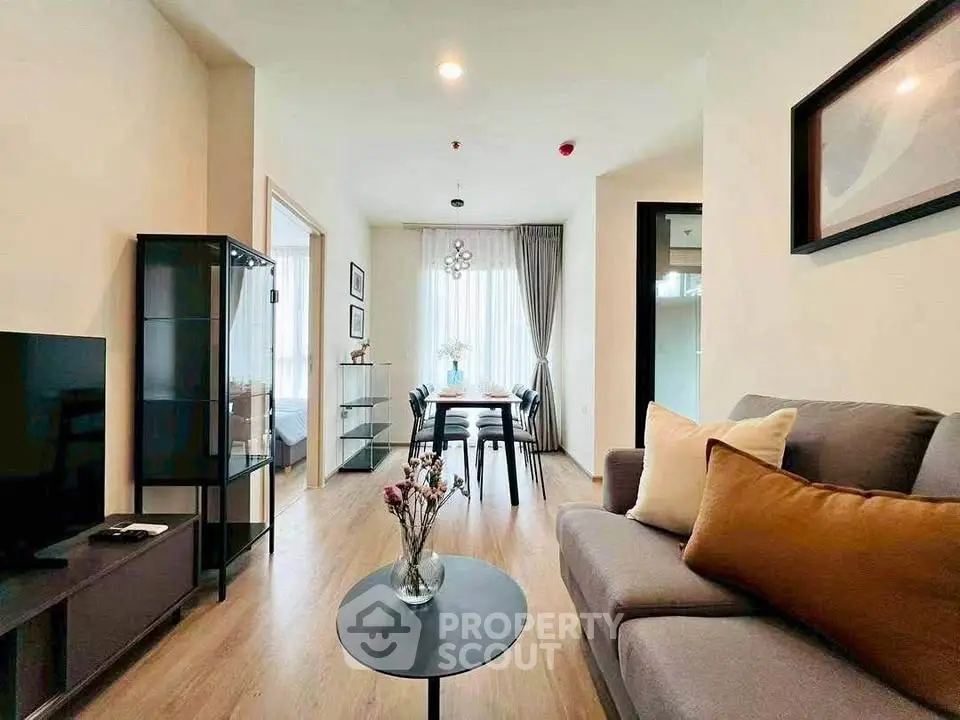 Modern living room with stylish decor and natural light, featuring a cozy sofa and dining area.