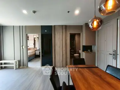 Modern open-plan living and dining area with stylish lighting and wooden accents.