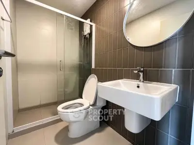 Modern bathroom with glass shower and sleek fixtures in contemporary apartment.